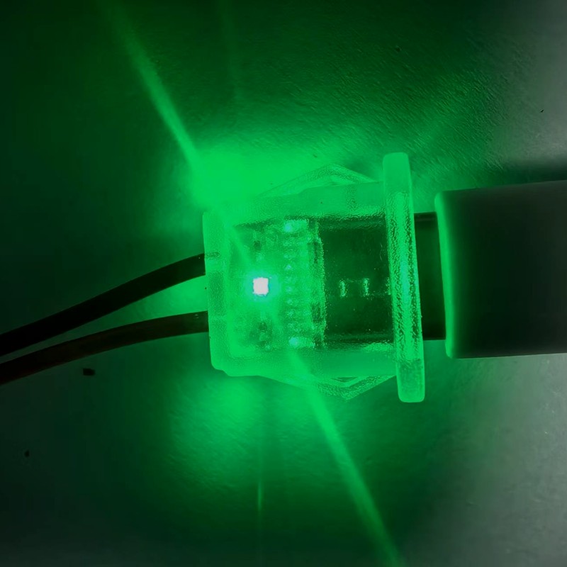 Sample 13 of 14: small LED indicator module with red and black pigtail leads, shown illuminated during production testing